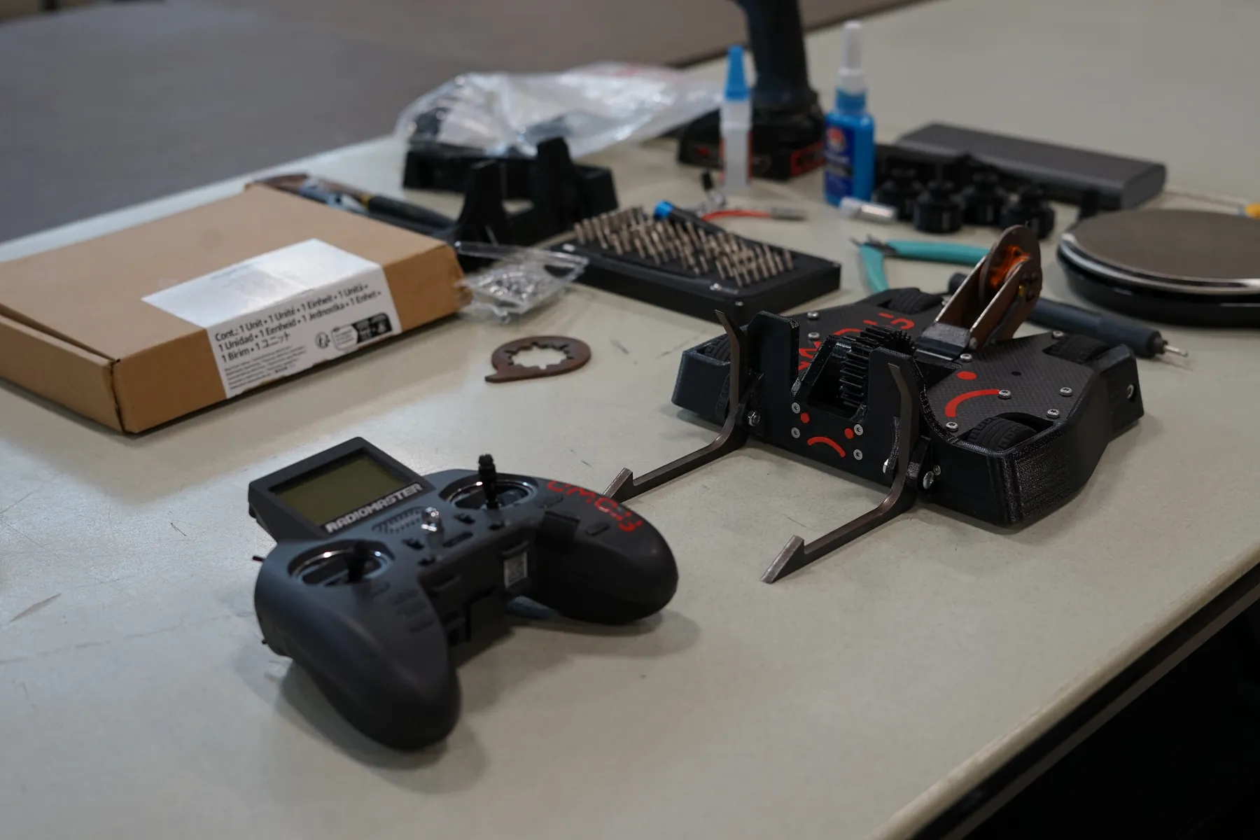Frown, a 3lb combat robot, on a workbench beside a RadioMaster transmitter and assembly tools